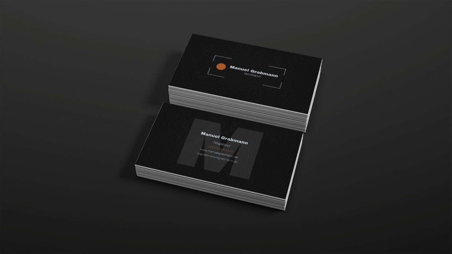 Visitenkarten Design für Regisseur Manuel Grabmann in Schwarz mit orangefarbenen Akzenten.