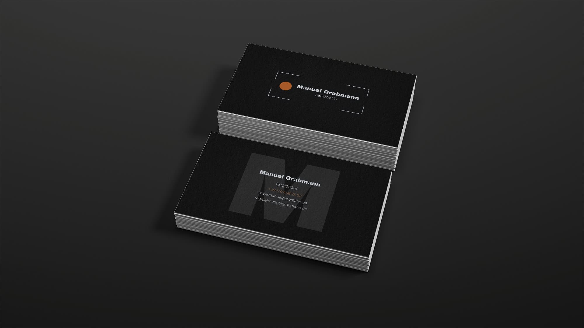 Visitenkarten Design für Regisseur Manuel Grabmann in Schwarz mit orangefarbenen Akzenten.